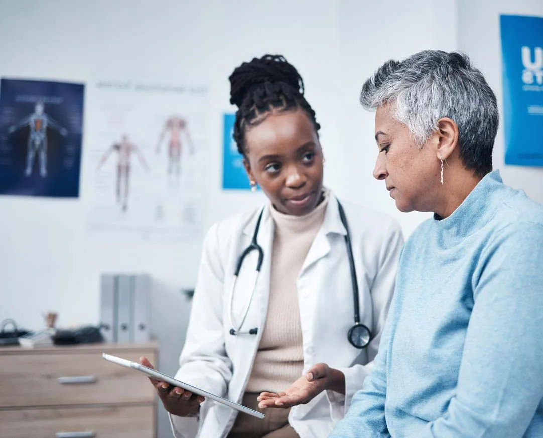 Female doctor showing tablet to a middle-aged woman during a consultation in a medical office.