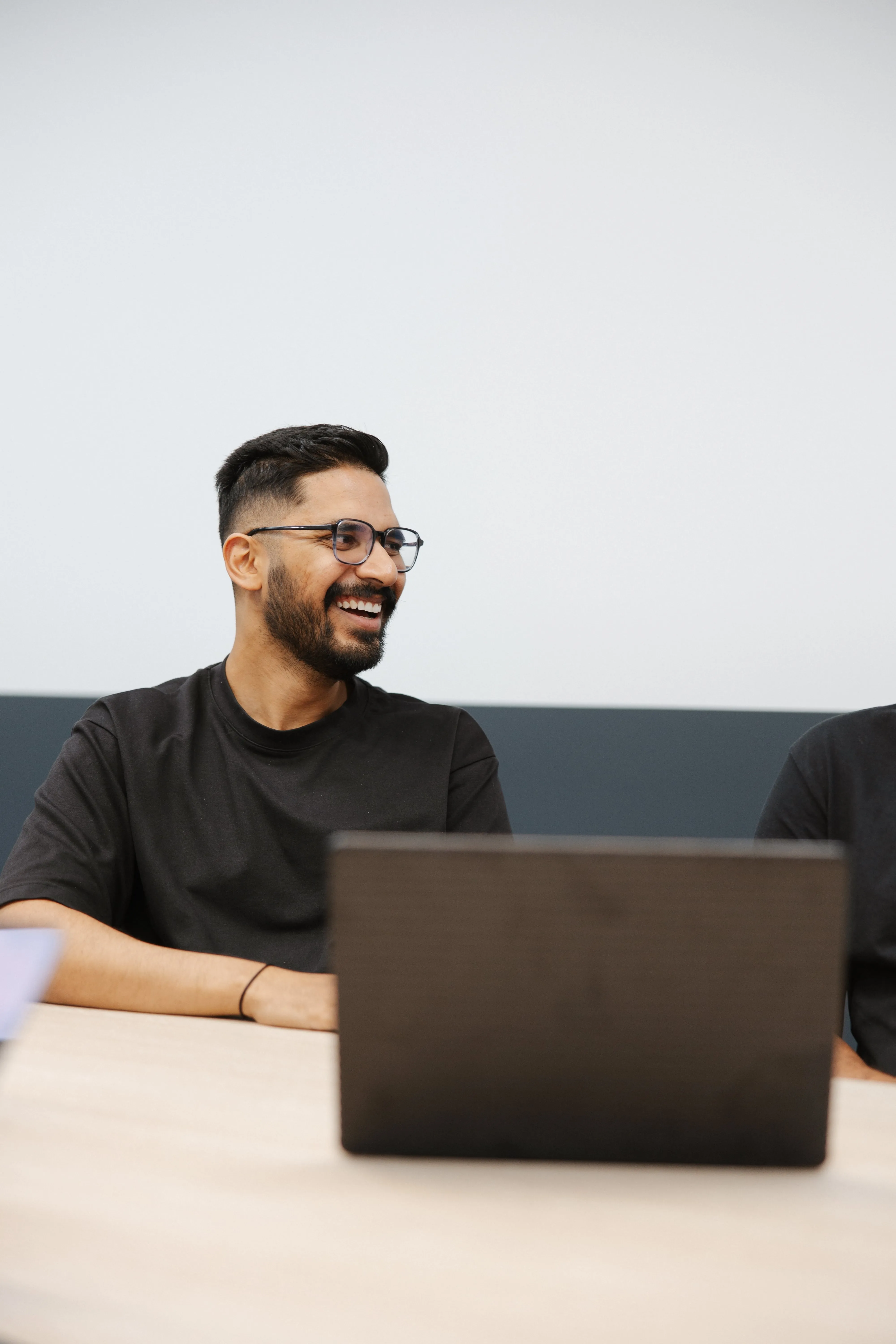 Two men sitting at a table with a laptop.
