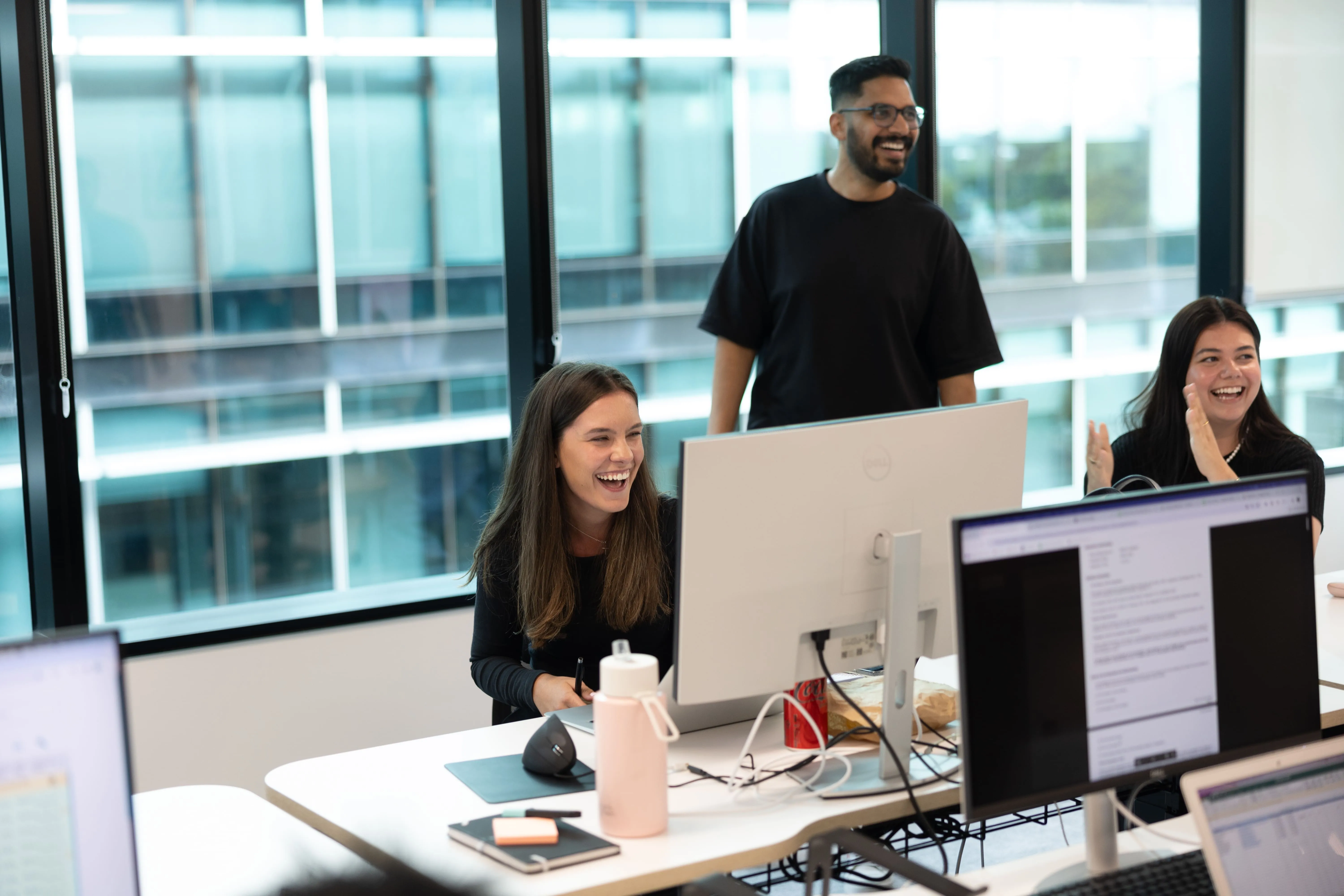 A group of people sitting at a table in front of computers.