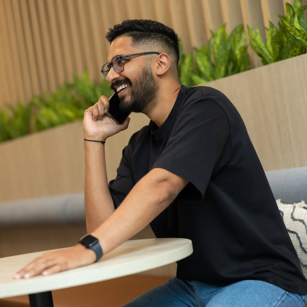 A man sitting at a table talking on a cell phone.