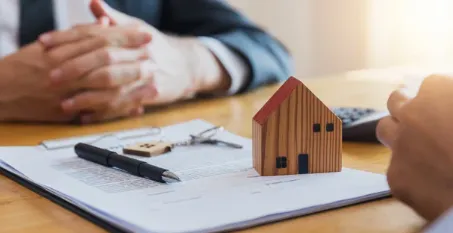 Investment property agreement with wooden house model keys and pen on contract paperwork during property consultation