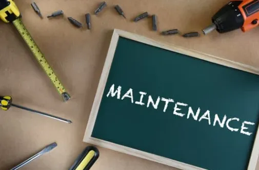 Maintenance concept with tools including screwdriver, drill, tape measure, and chalkboard with 'MAINTENANCE' text on workbench background