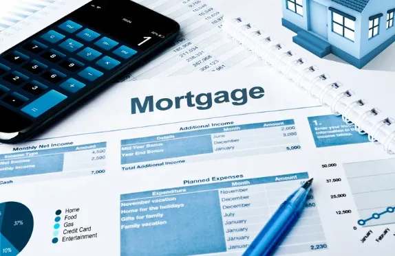 Mortgage budget sheet with financial planning tools including calculator, pen, notebook, and miniature house model—representing real estate investment budgeting and expense tracking.