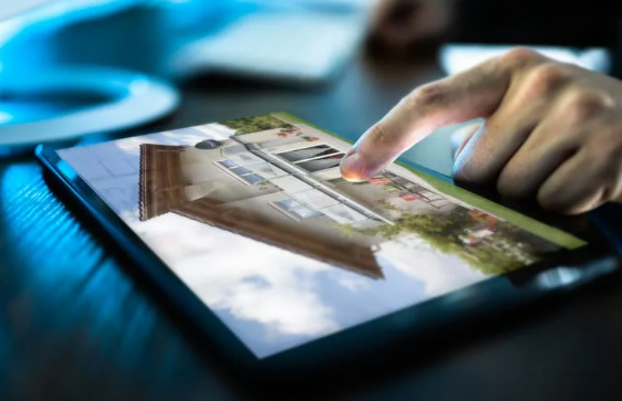 Person browsing a property listing on a digital tablet, with a modern house displayed on the screen—symbolising online real estate search or digital home buying.