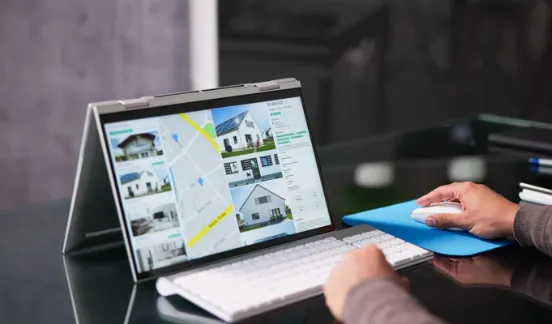 Small wooden house model with a magnifying glass symbolising property search and real estate inspection.