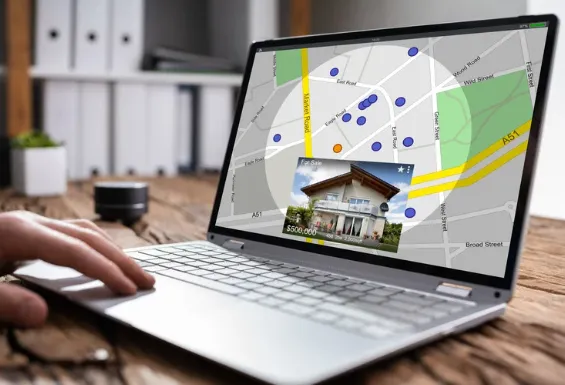 Person using a laptop to view an interactive property map showing houses for sale, location markers, and real estate price details.