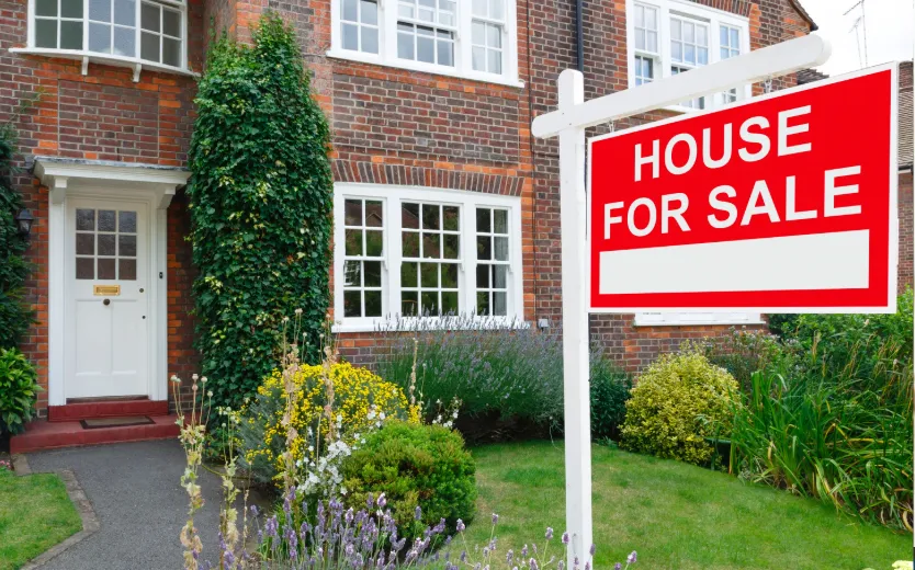 : Residential house with red For Sale sign in front yard, representing property sales and real estate investment opportunities.