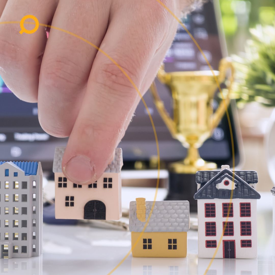 Hand picking miniature house model among different properties, symbolizing real estate investment and property selection.