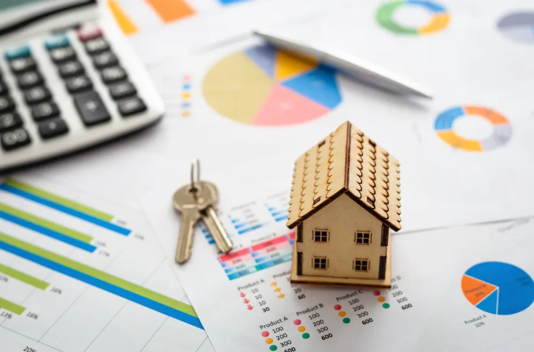 Miniature house and keys placed on financial charts with graphs and calculator, symbolising property investment analysis in Australia.