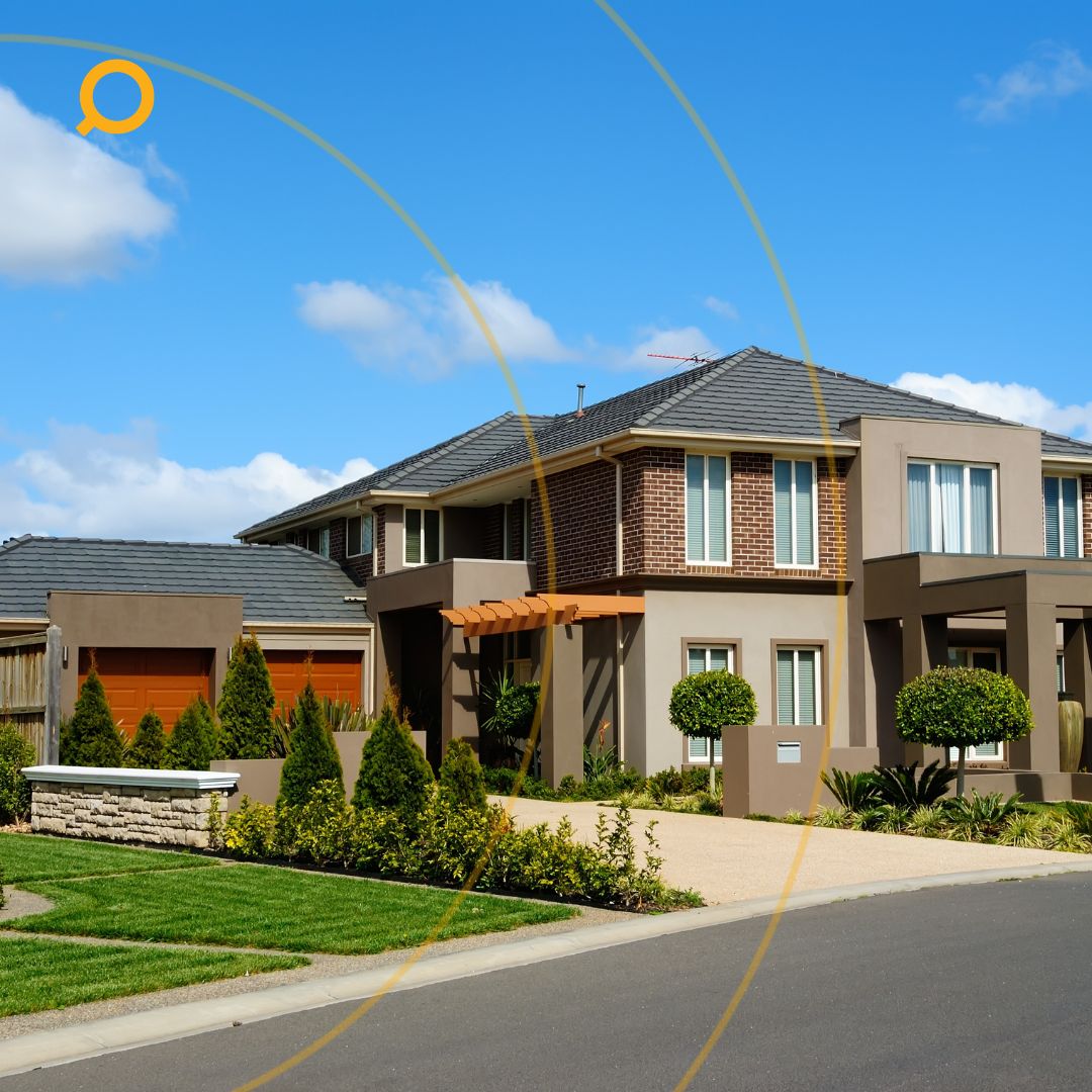 Modern Australian double-storey suburban house with landscaped front yard, trimmed hedges, and a paved driveway under a bright blue sky.