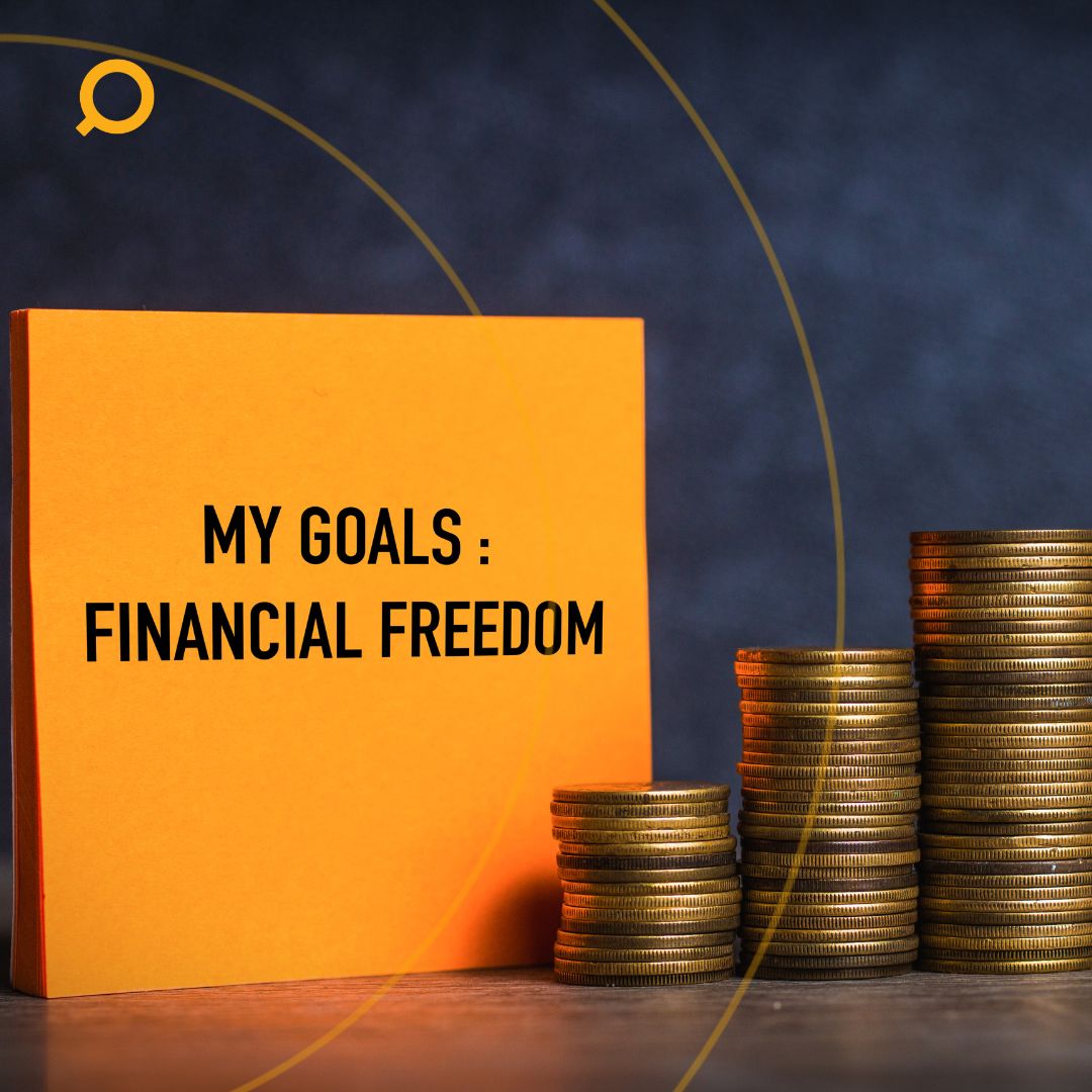 A yellow note with a text that says: Goals: Financial Freedom beside a stack of coins