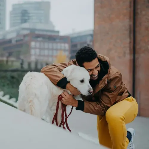 a man is petting a white dog on a leash
