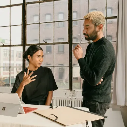 a man standing next to a woman in front of a laptop