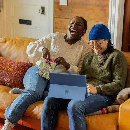 a couple of people sitting on a couch with a laptop