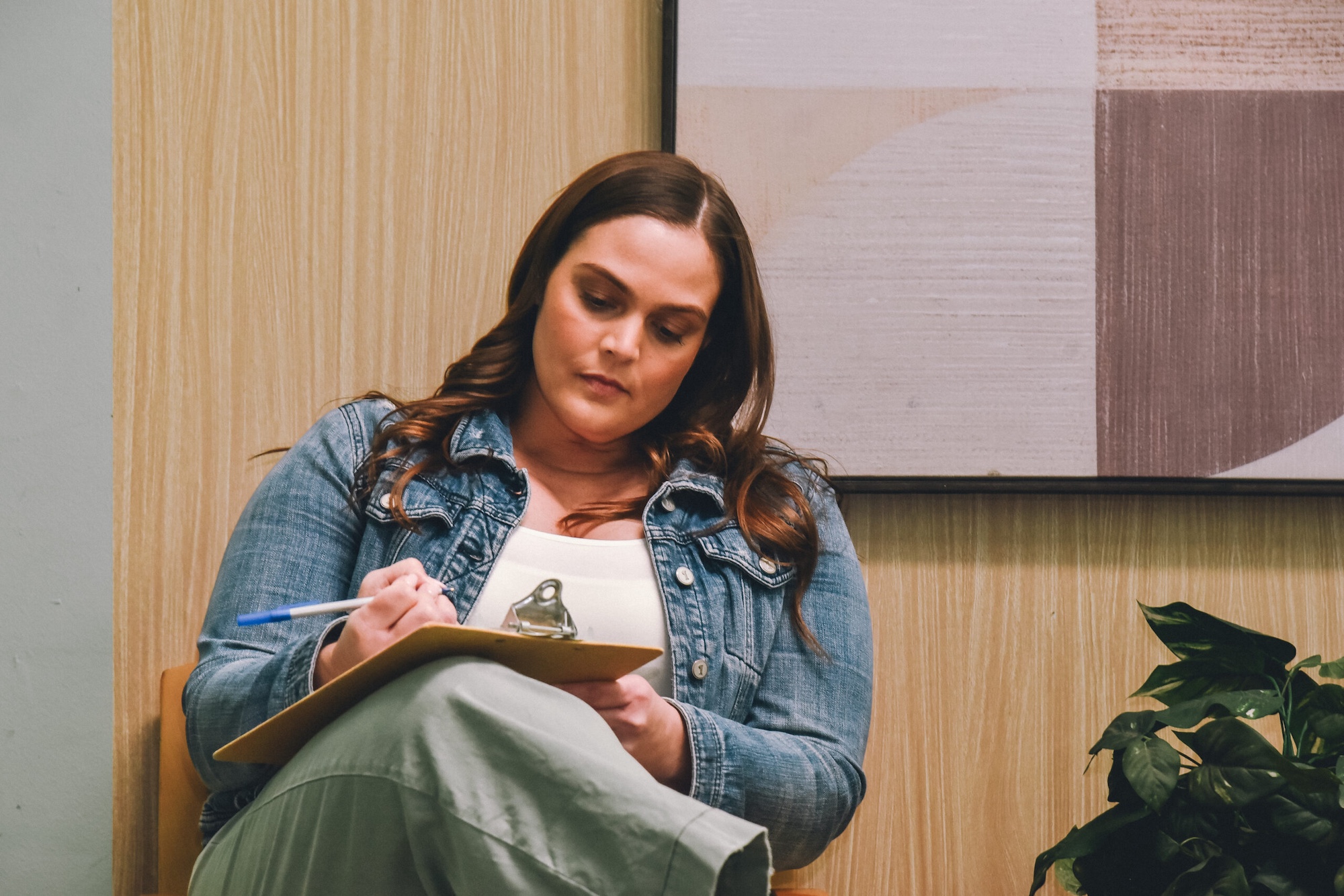 A seated woman filling out a form on a clipboard