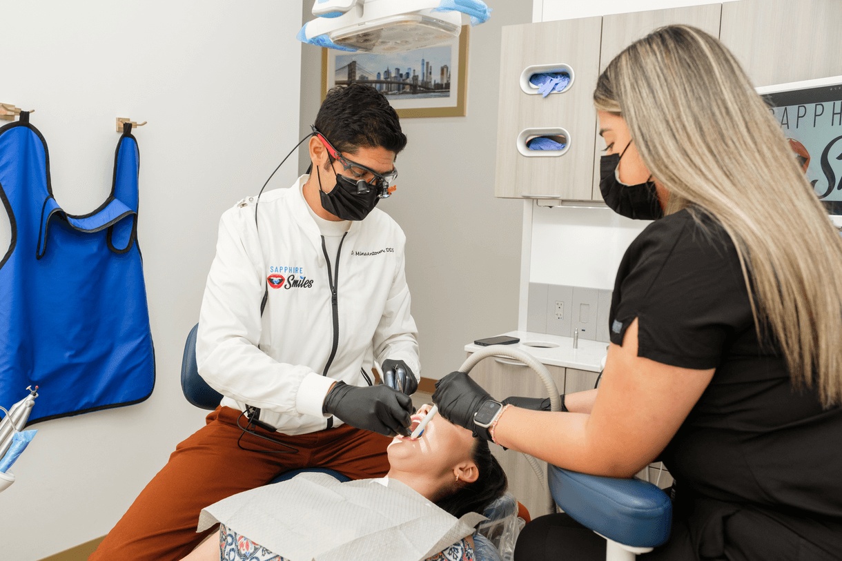 Dentist and assistant providing periodontal care to a patient in a modern clinic, highlighting treatment from the best periodontist in Houston.