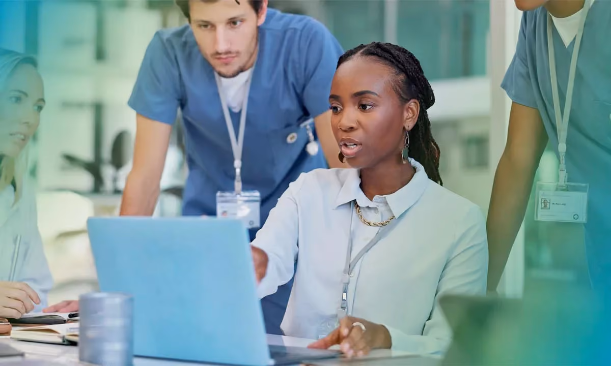 Group of healthcare professionals huddled around a computer