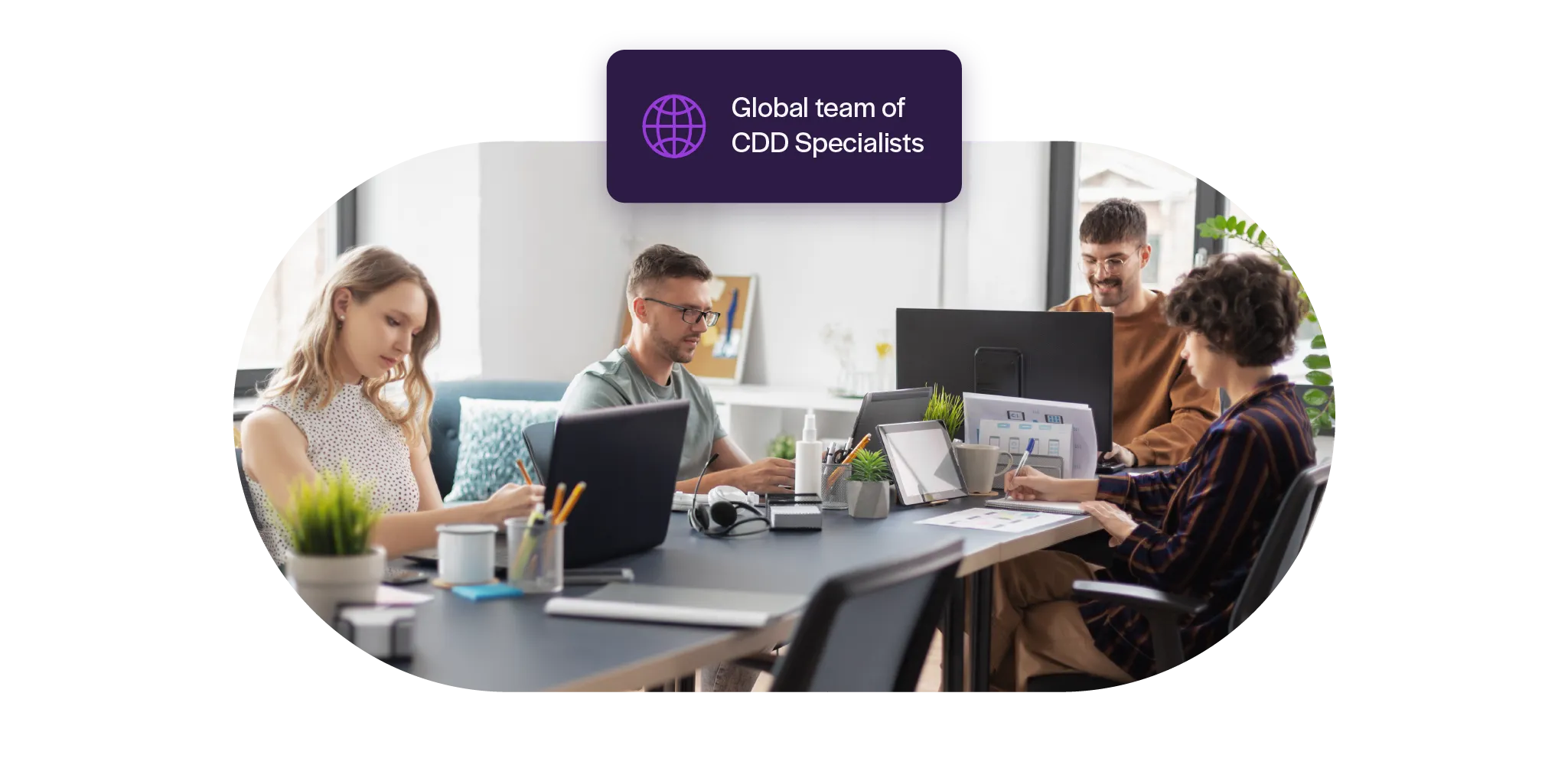 Four people working collaboratively at a desk with laptops and documents in a bright office, labeled as a global team of CDD specialists.