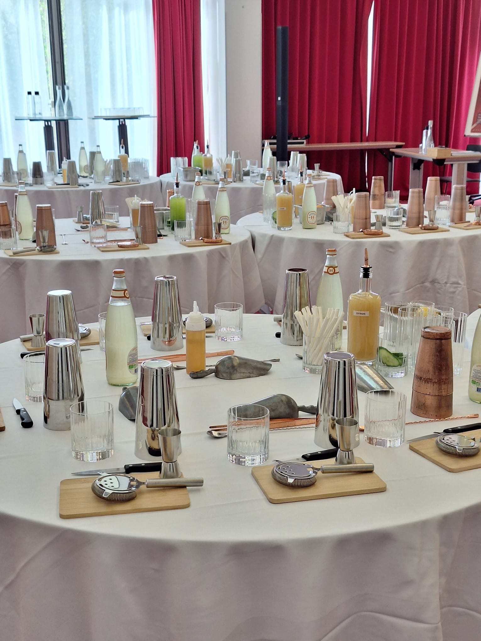 Tables dressées pour un atelier cocktail : shakers, verres et ingrédients prêts pour les participants