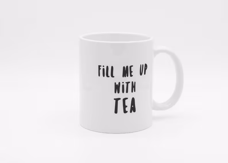 White ceramic mug with black text saying 'FILL ME UP WITH TEA' on the side.