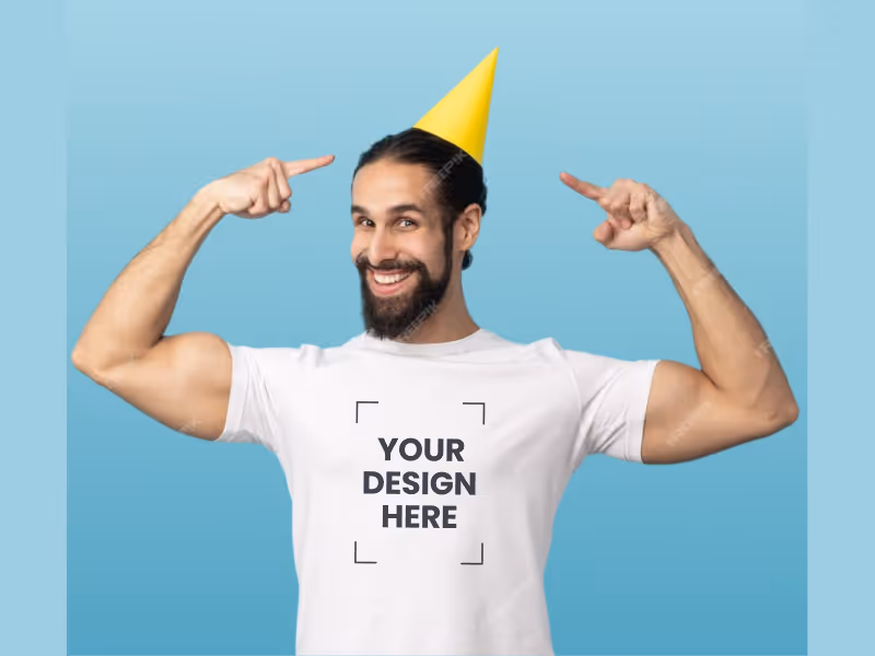 Smiling man wearing a yellow party hat and white t-shirt with 'Your design here' text, pointing at his hat against a blue background.
