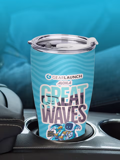 Blue travel tumbler with 'Gearlaunch Aloha Great Waves' text and cartoon astronaut surfing waves design, placed in a car cup holder.