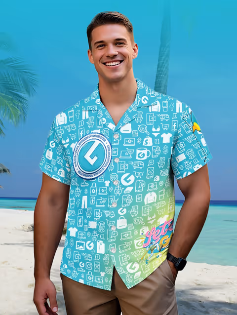 Smiling man wearing a blue and green graphic tropical shirt standing on a beach with palm trees and ocean in the background.