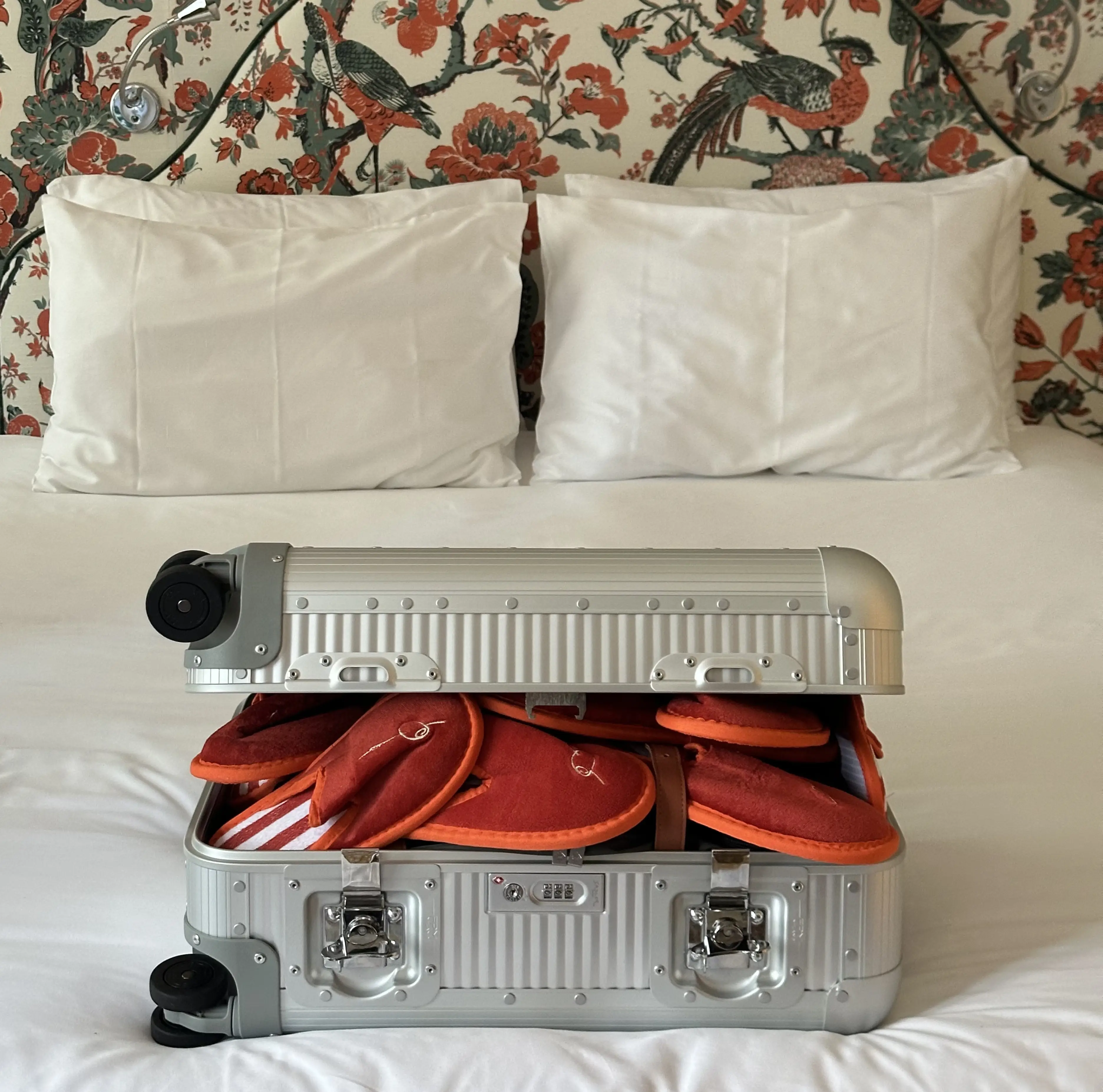 Open suitcase packed with summer essentials on a hotel bed