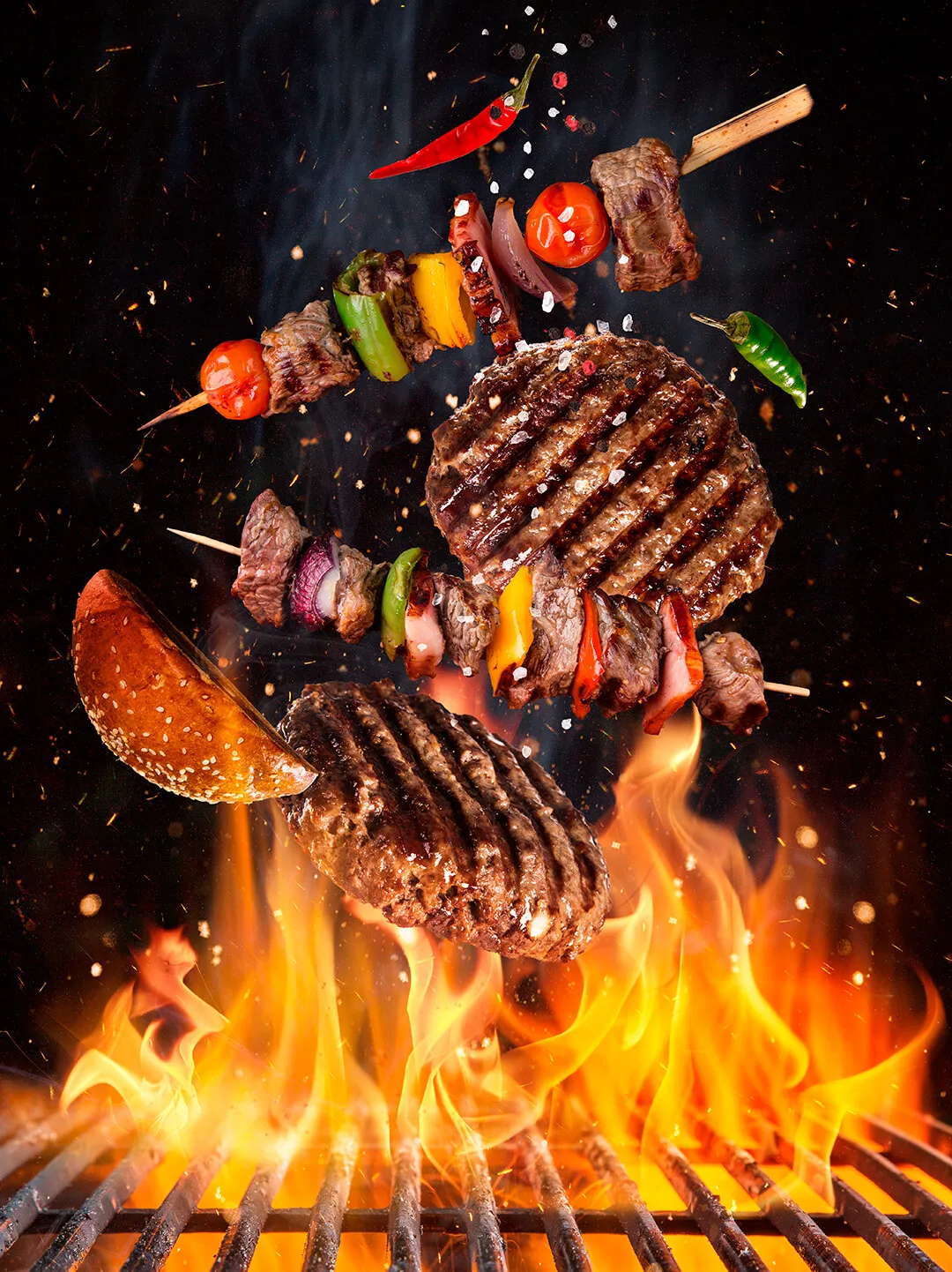 Gegrillte Burgerpatties, Fleischspieße mit buntem Gemüse und Chilischoten über offenem Feuer auf dem Grill.