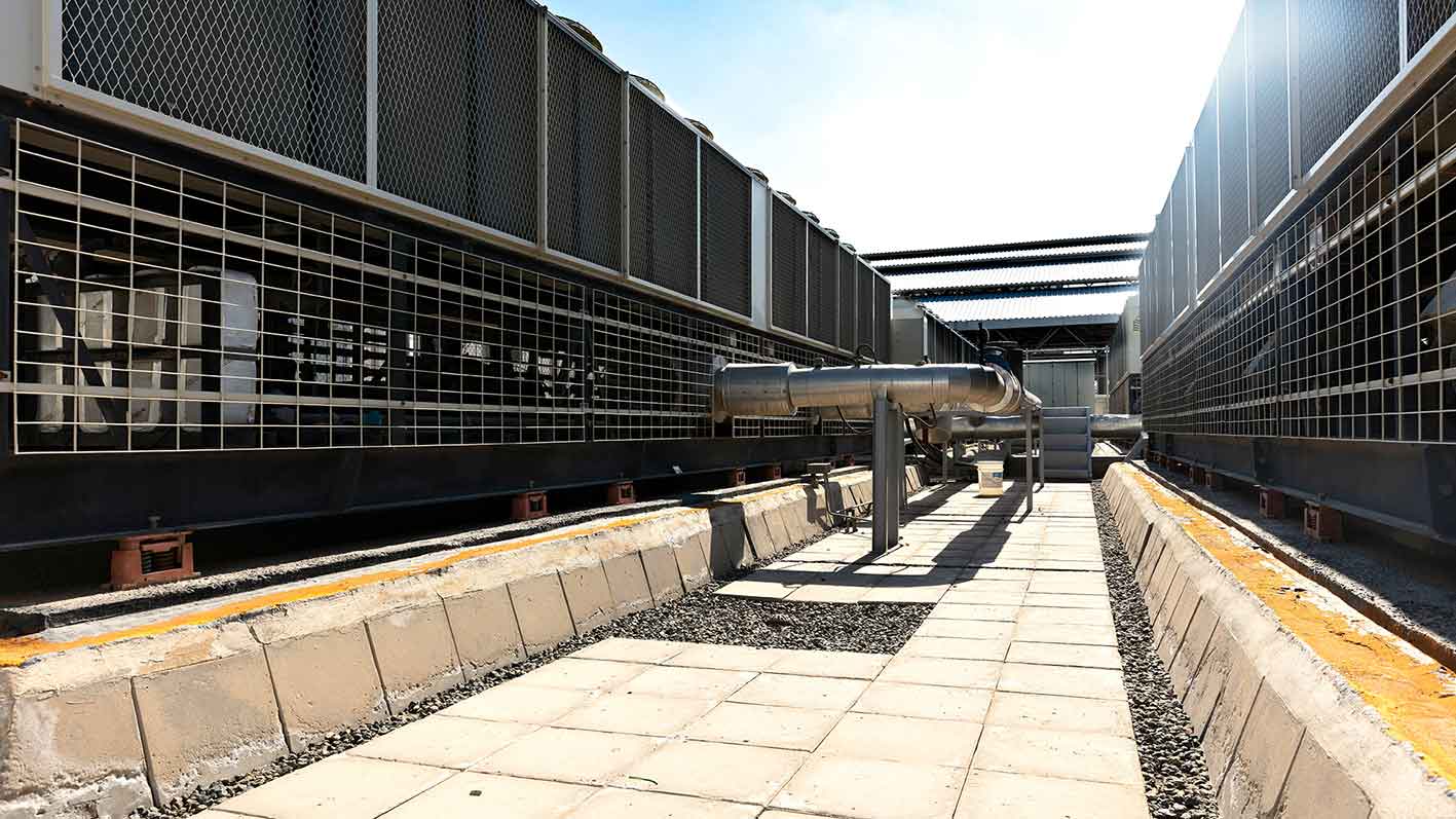 Rooftop HVAC plant with cooling units and hydronic piping installed as part of a commercial building services system.