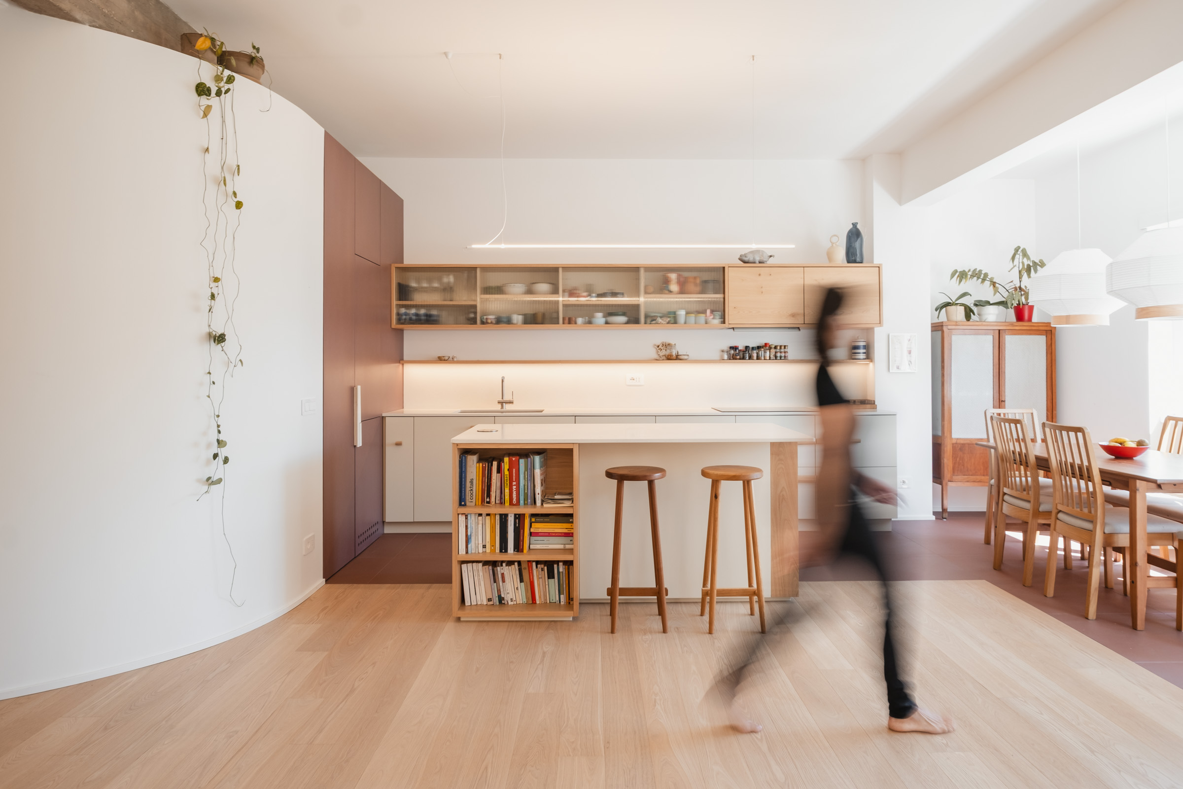 Appartamento pensato per una giovane famiglia, caratterizzato da una parete curva all’ingresso che smorza la lunghezza del corridoio e gioca con la luce naturale, creando continuità e dinamismo. Una porta con vetro bacchettato illumina la parte iniziale più buia del percorso.
Un attento gioco di volumi ha trasformato gli spazi contenitore in elementi architettonici, ottimizzando ogni area. La cucina integra dispensa e frigo, mentre la camera padronale include una testiera con nicchie per i comodini.
Il parquet in frassino dai toni neutri unifica l’intero appartamento. Gres, cotto smaltato a mano e resina dai colori neutri si alternano con coerenza, arricchendo l’insieme senza spezzarne l’unità.
Una trave in calcestruzzo a vista contrasta con i materiali caldi degli interni, aggiungendo un tocco deciso al progetto. Il progetto è stato redatto in collaborazione con la falegnameria Mattia Migliorati woodworker che ha realizzato tutte le falegnamerie su misura. 