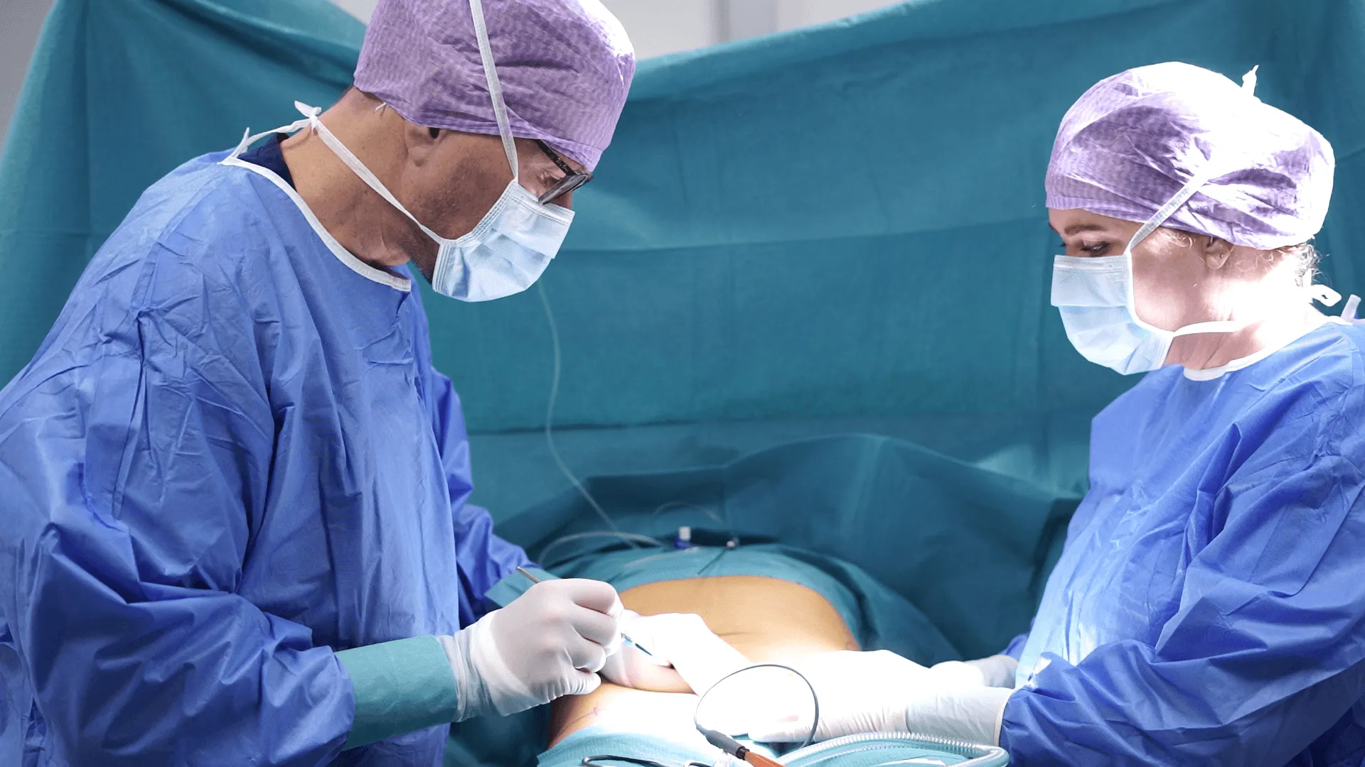 A couple of doctors performing surgery on a patient.