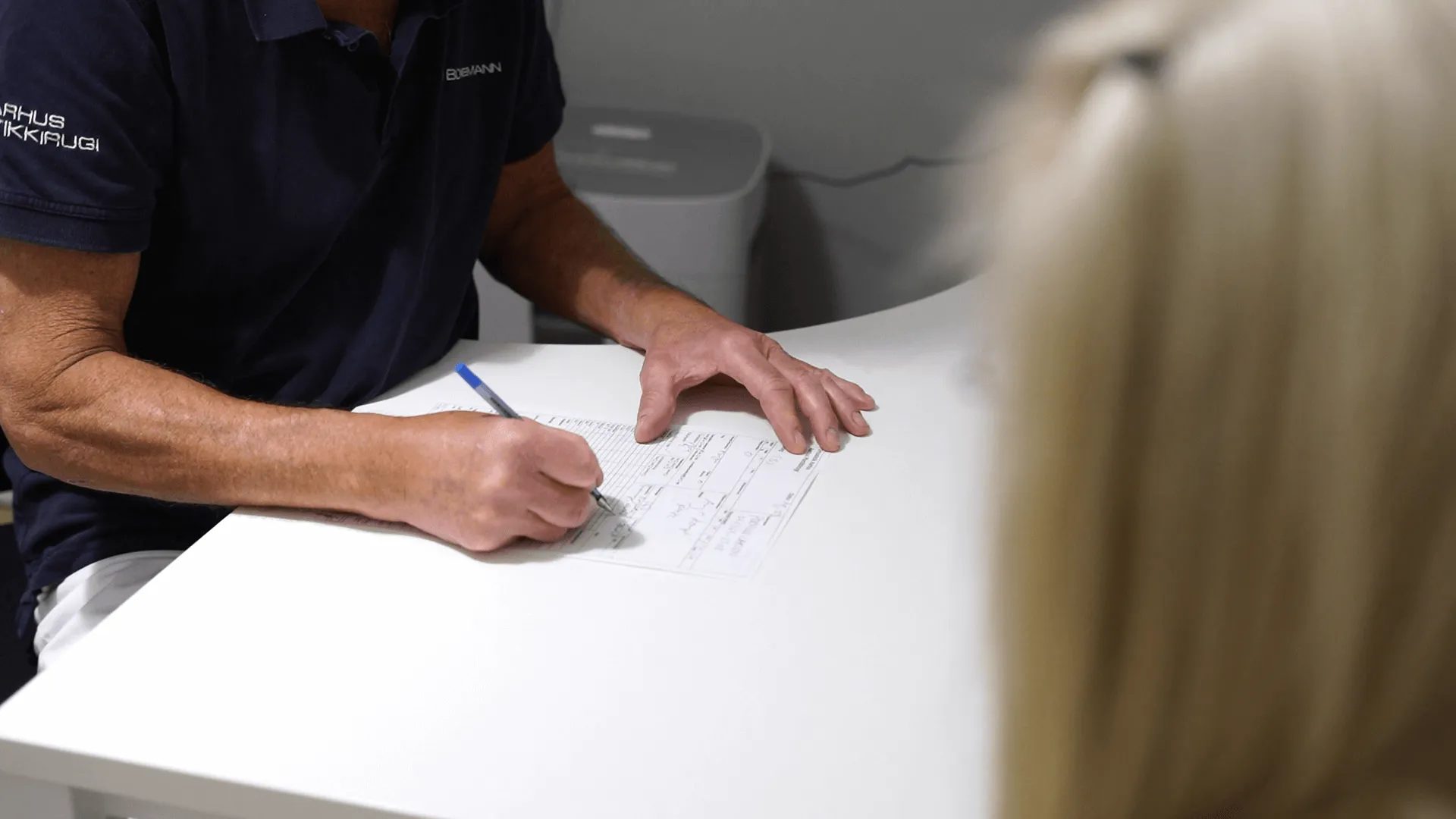 A man sitting at a table writing on a piece of paper.