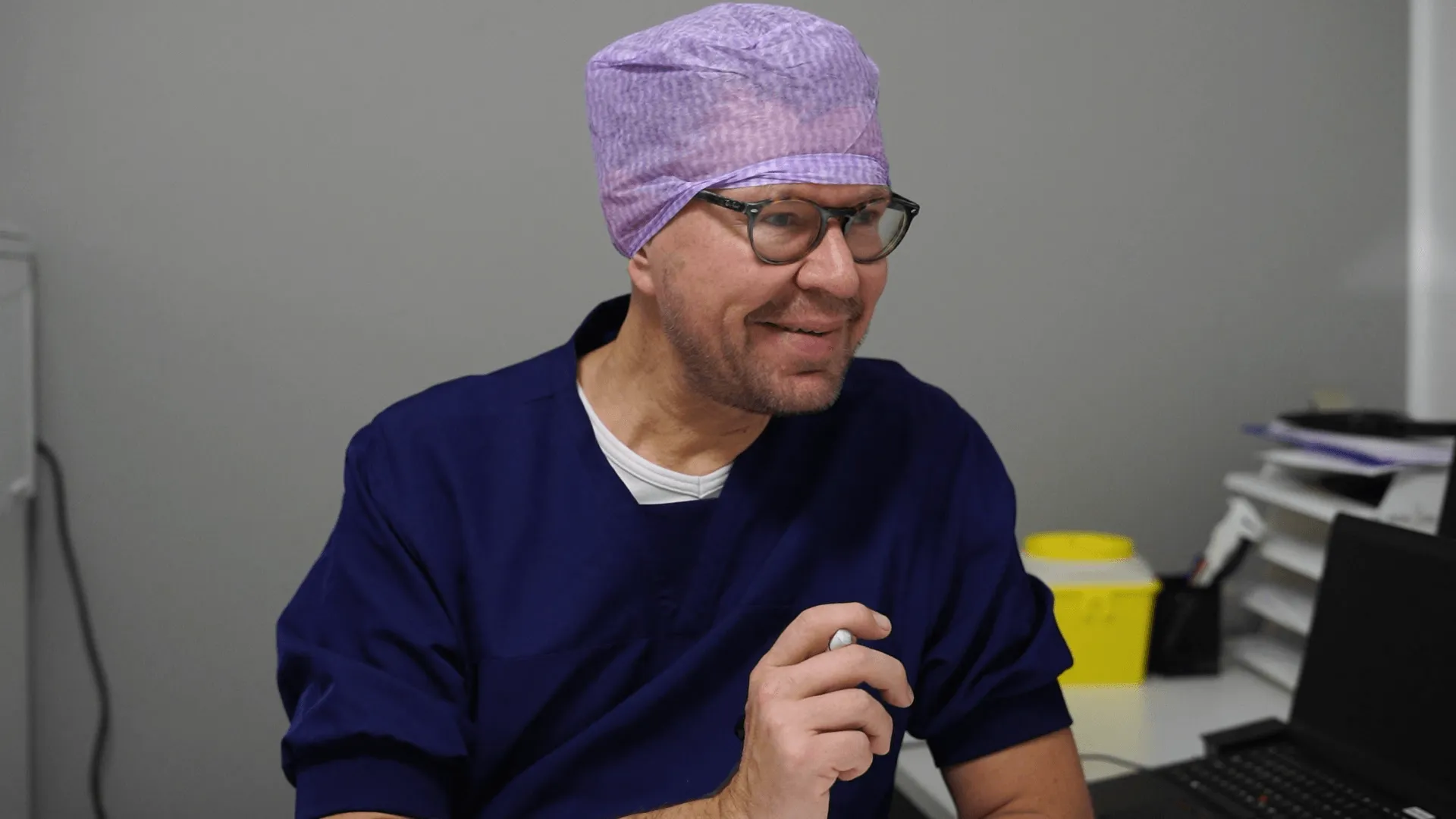 A man wearing a purple hat is looking at a laptop.