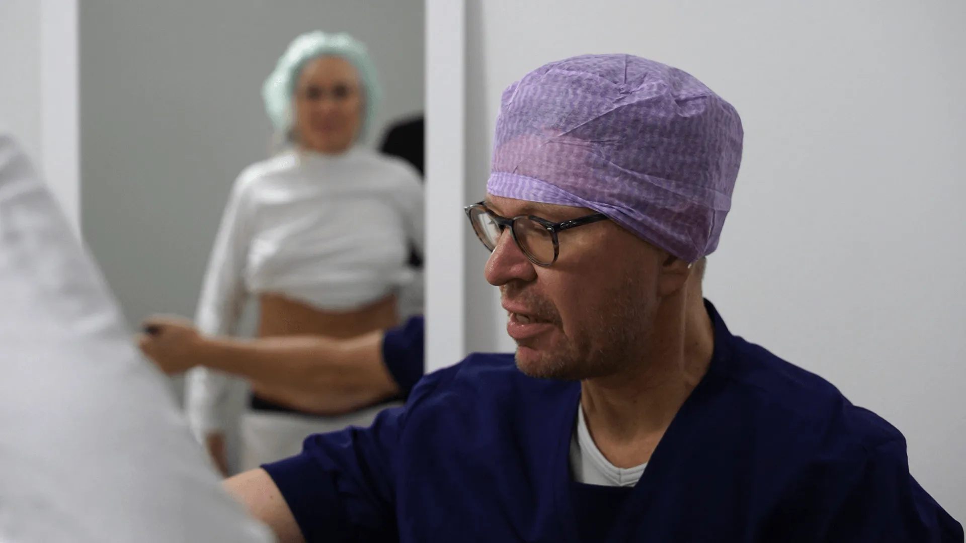 A man in a surgical garb looks at a piece of paper.
