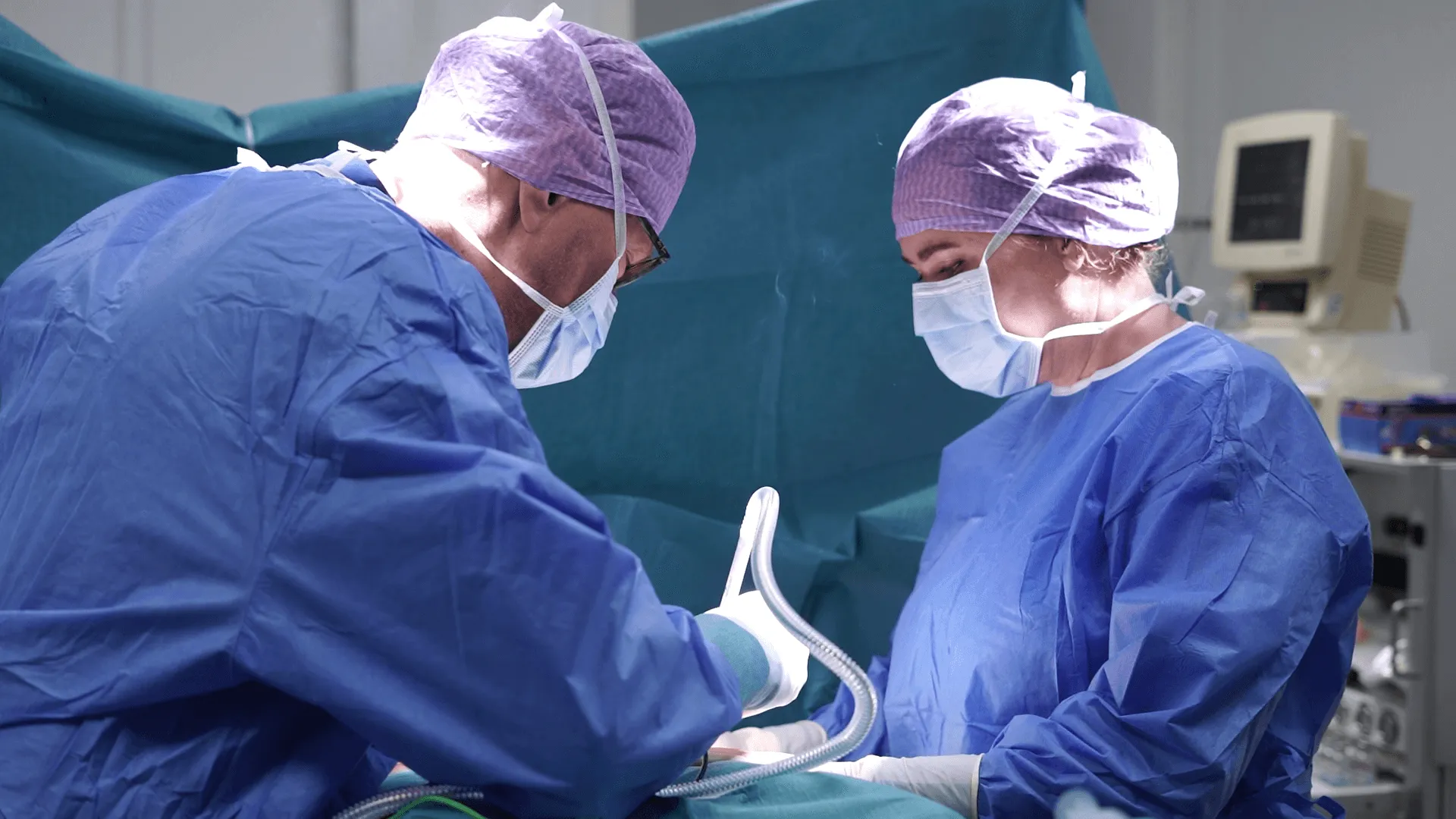 A couple of doctors performing surgery on a patient.