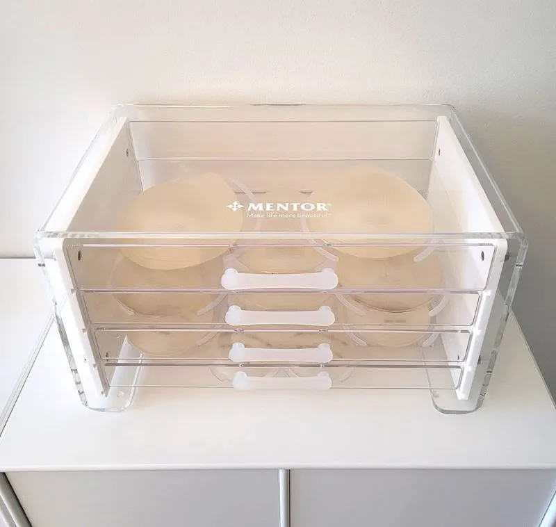A stack of white plates in a plastic container.