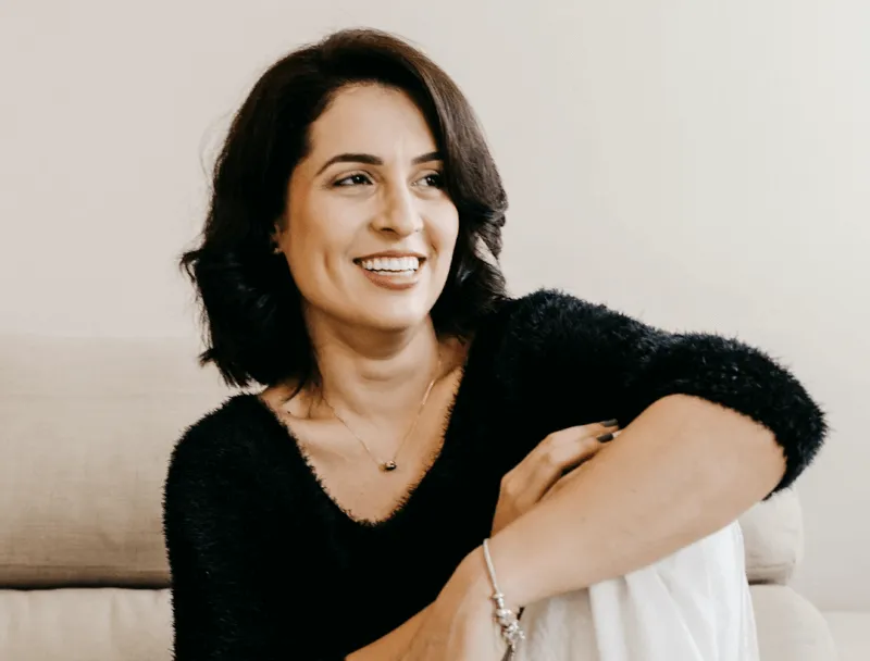 A woman sitting on a couch smiling at the camera.