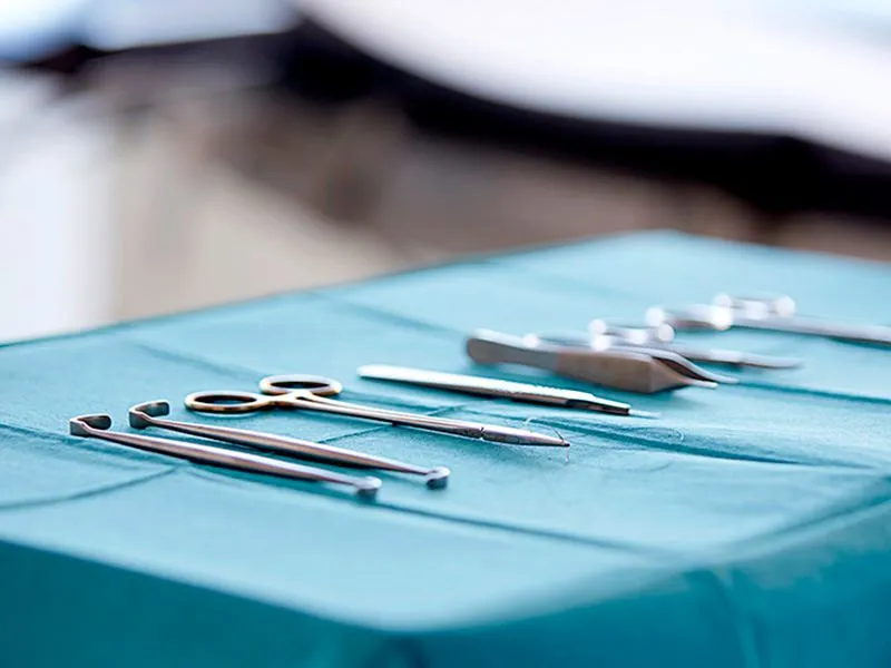 A table topped with surgical instruments on top of a blue table.