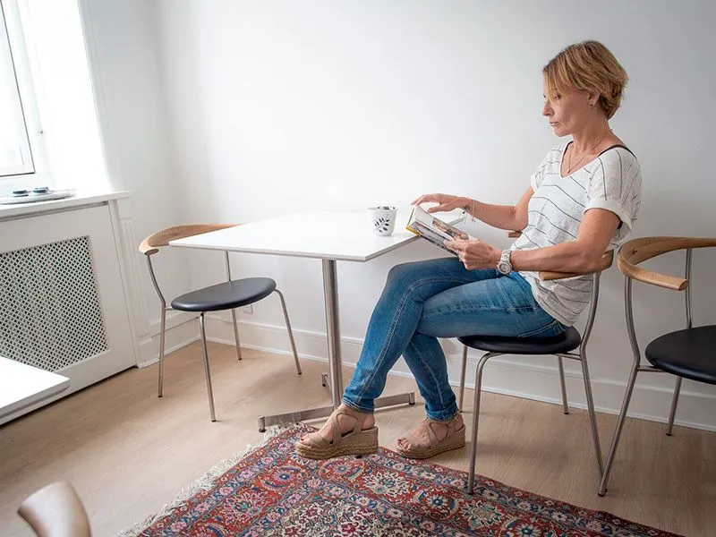 A woman sitting at a table reading a book.