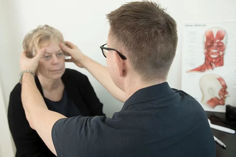 A doctor measuring a womans face with his hands