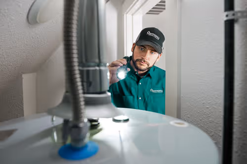 Happy golden retriever puppy sitting in a muddy puddle on green grass in a backyard.
