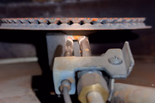 Frozen icicles hanging from a copper pipe in a crawl space with ice pooled on the ground.