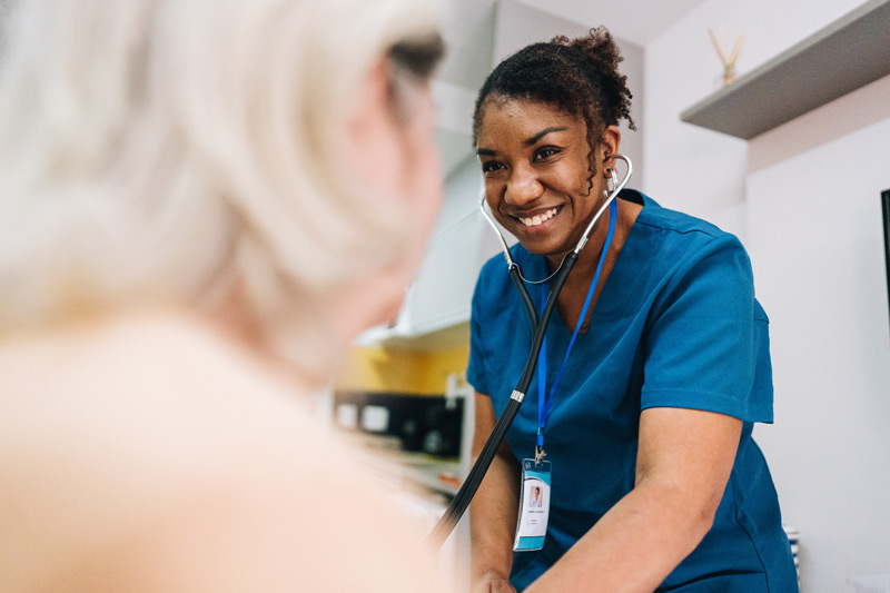 Nurse using a stethoscope on a patient