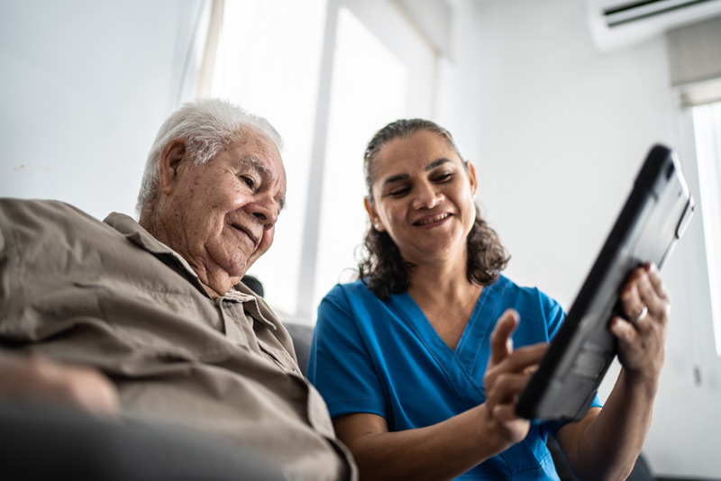 Nurse holding an ipad with an elderly patient