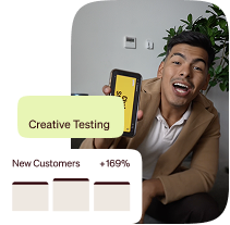 Man holding a smartphone beside a creative testing dashboard showing a 169% increase in new customers.