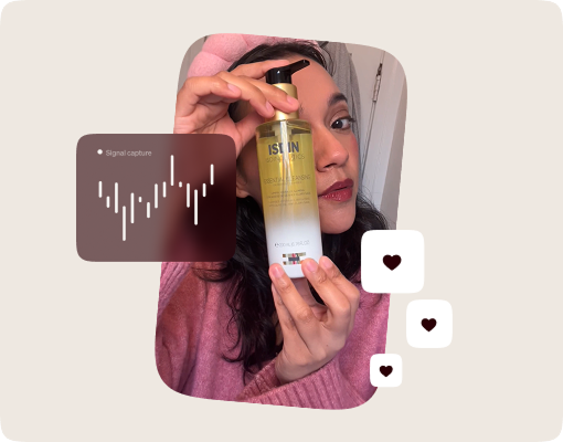 Woman with a pink headband holding a bottle of Isdin body oil lotion near her face.