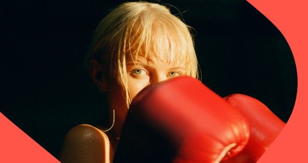 A woman with blonde hair and a red boxing glove on.