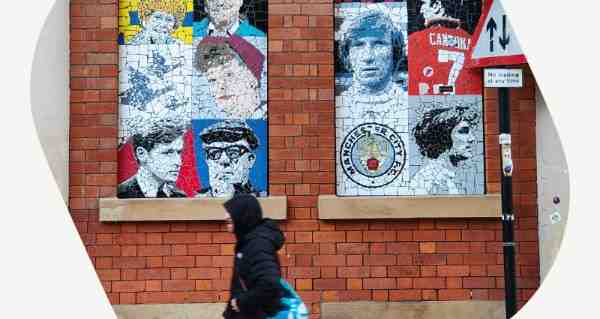 A woman walking past a brick wall with a mosaic of people on it.