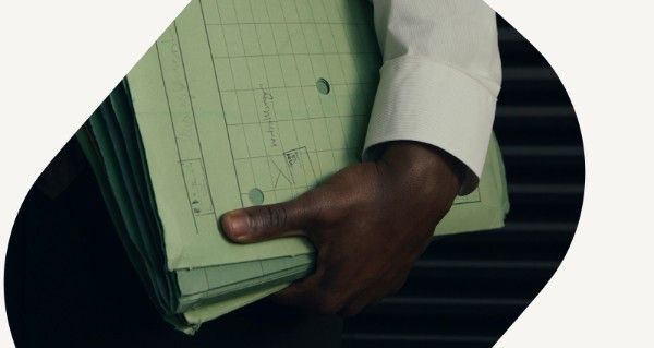 A man holding a green book with a white shirt on.